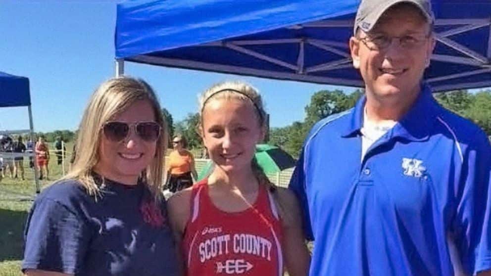 A man and a woman standing by a little girl in the middle